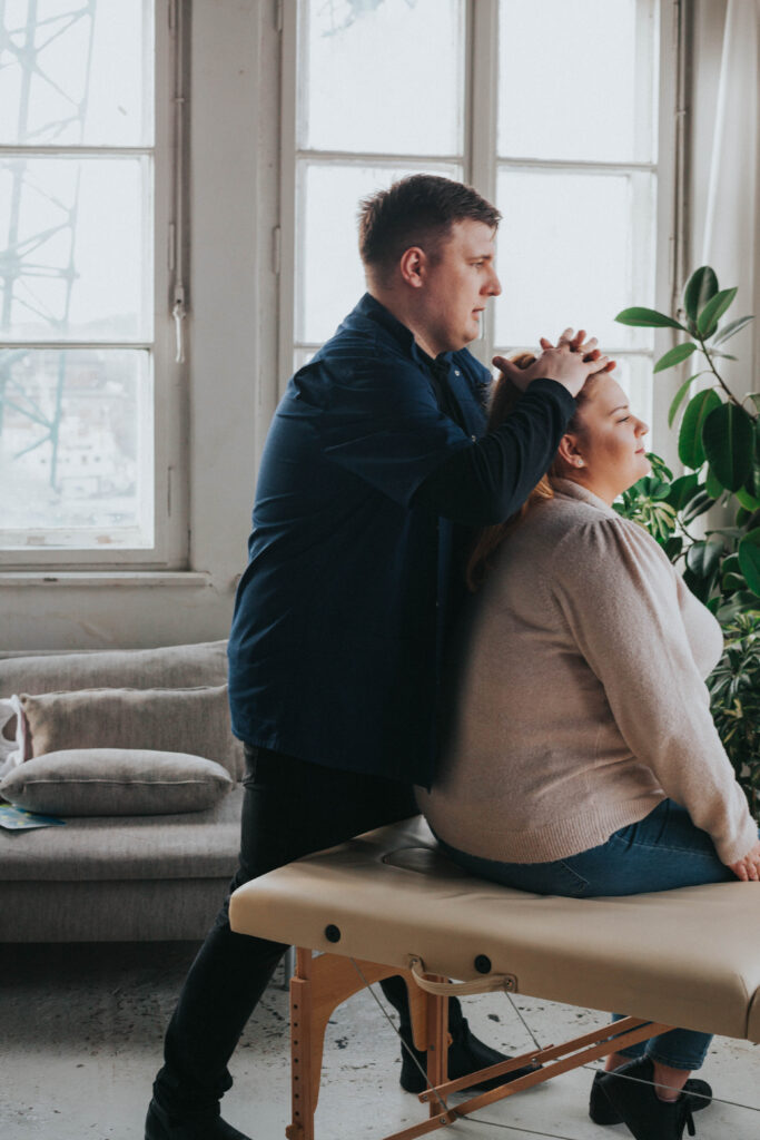 Fizjoterapeuta Łukasz Kusowski ćwiczący z pacjentką na łóżku do fizjoterapii