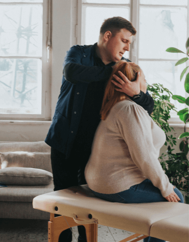 Fizjoterapeuta Łukasz Kusowski ćwiczący z pacjentką na łóżku do fizjoterapii - terapia