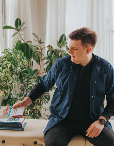 Fizjoterapeuta Łukasz Kusowski sięgający po książkę