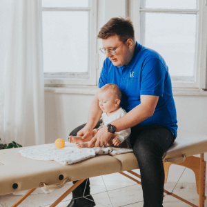 Fizjoterapeuta Łukasz Kusowski ćwiczący z niemowlakiem na stole do fizjoterapii