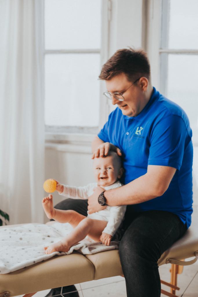 Fizjoterapeuta Łukasz Kusowski trenujący z uśmiechniętym dzieckiem