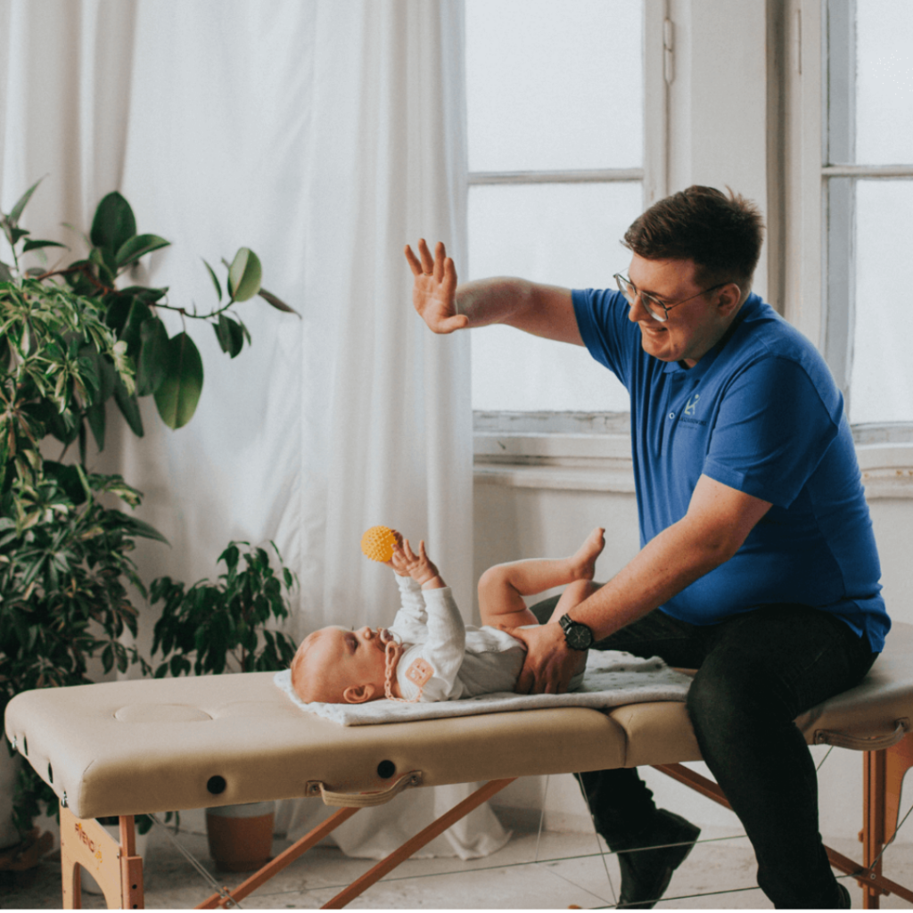 Fizjoterapeuta Łukasz Kusowski ćwiczący z niemowlakiem na łóżku do fizjoterapii
